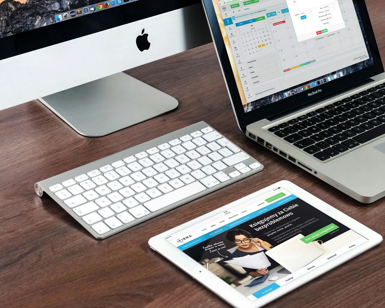 A desk setup with a computer, laptop, tablet, keyboard, and mouse.
