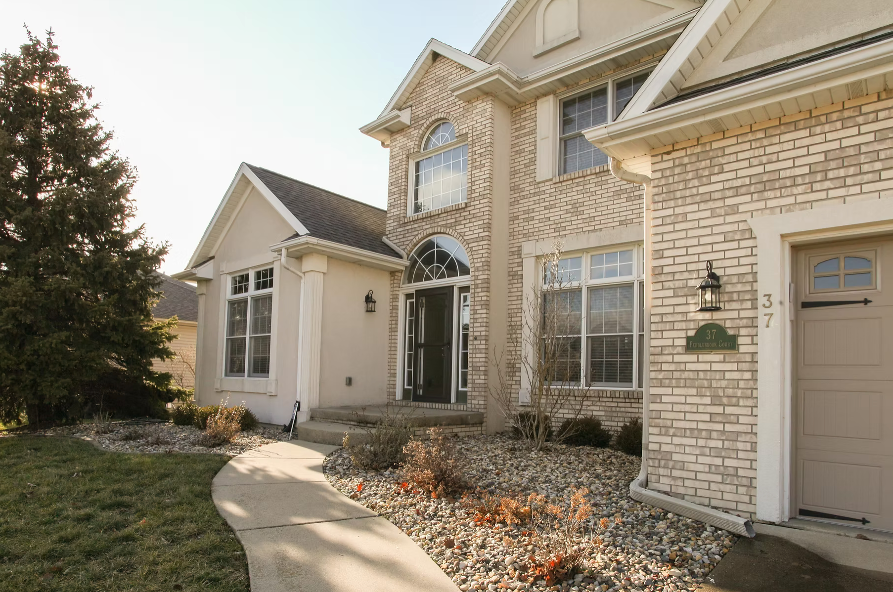 approach view of a white brick home heading to front door