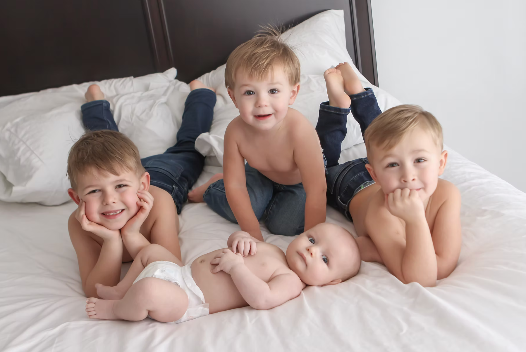 four boys smiling on parents bed
