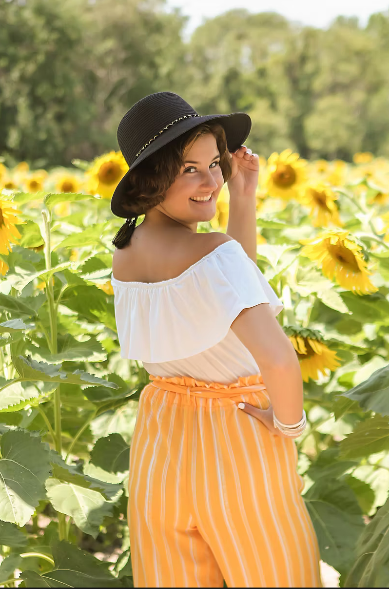 senior girl with a hat by a sunflower field