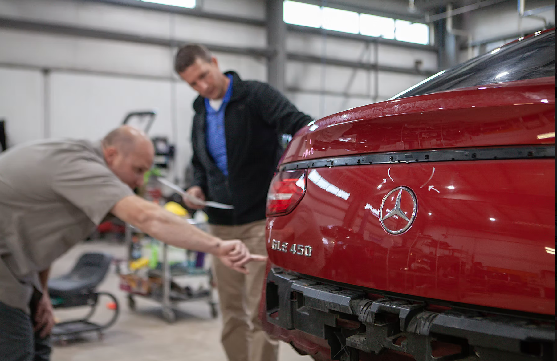Two men talking about damage of a car in a body shop