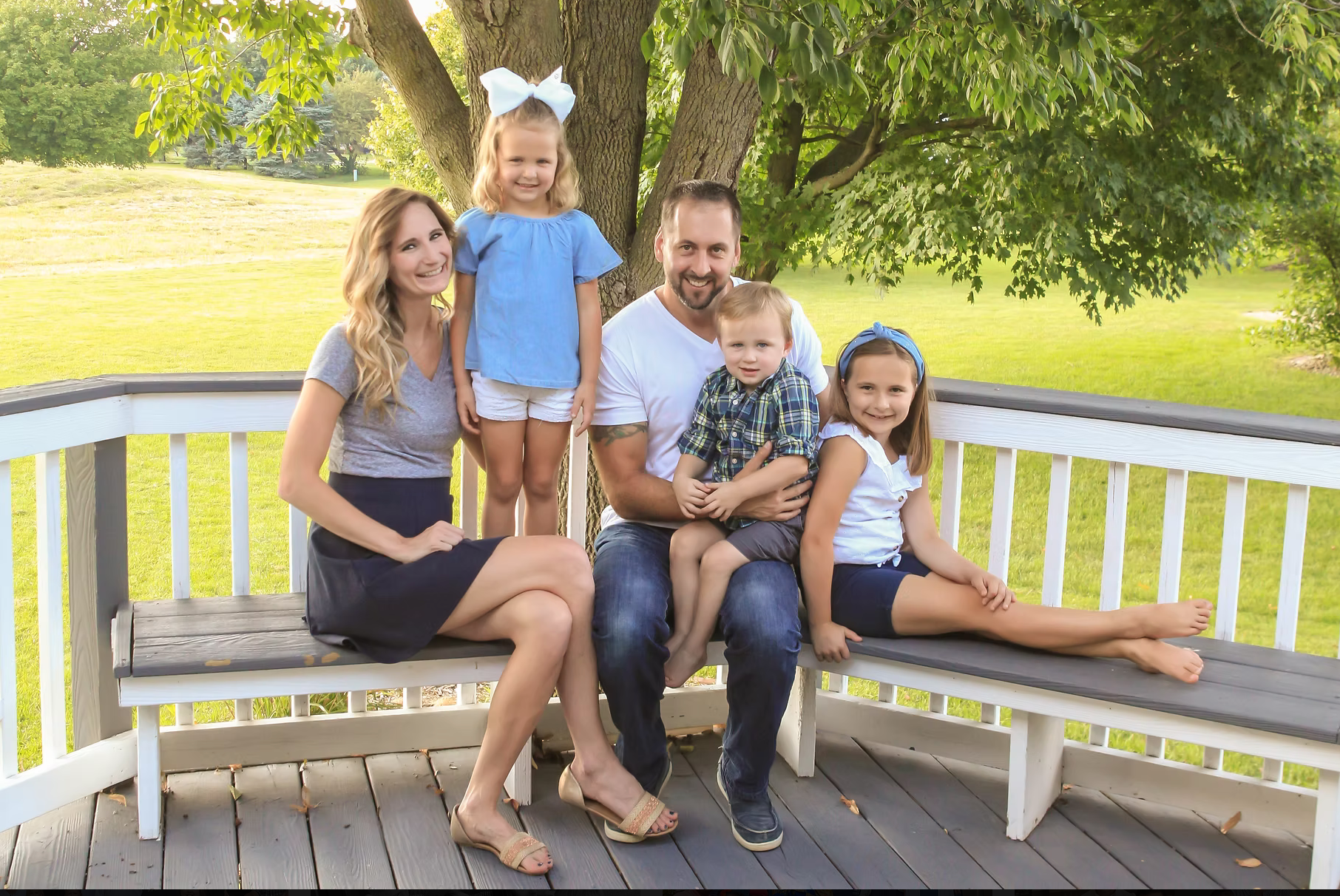 family of 5 sitting on their back deck smiling