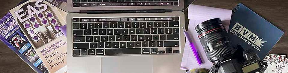 Laptop, camera, and magazines on a desk