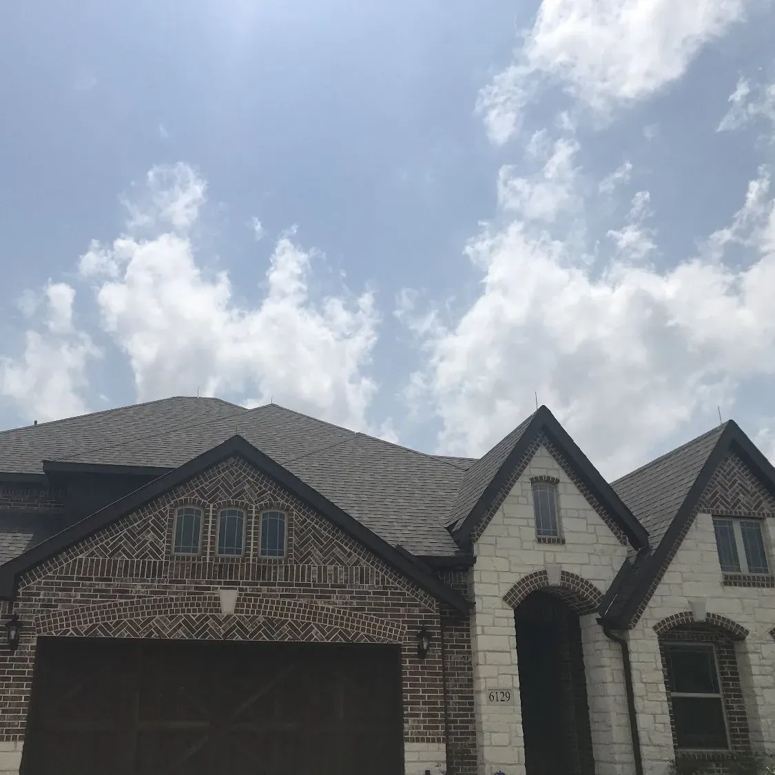 A house with a gray roof and a blue sky with clouds in the background.