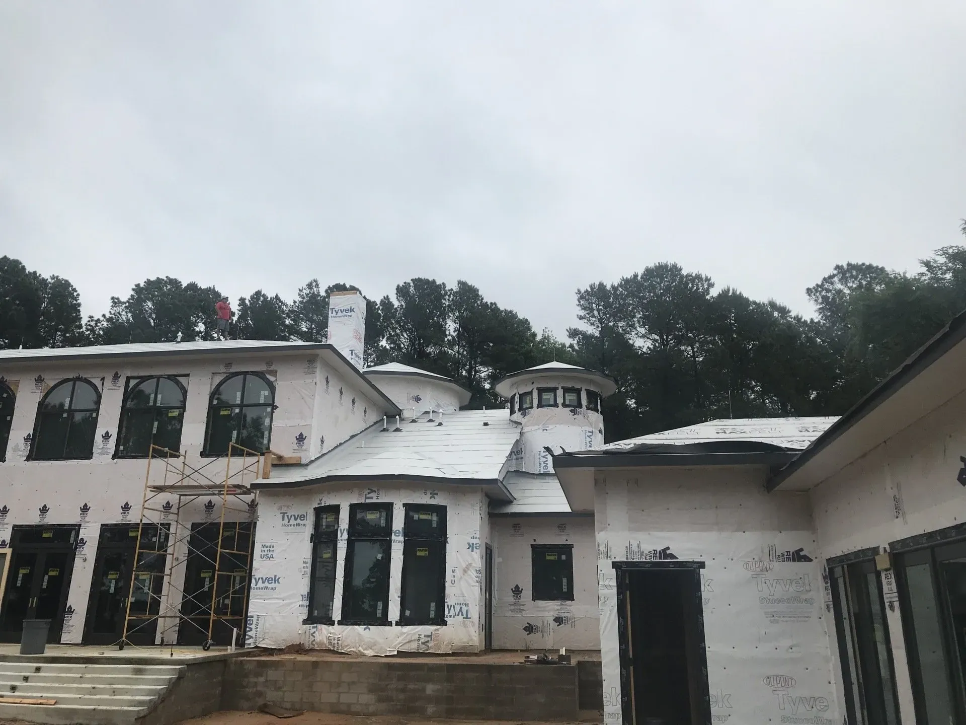 A large white house is being built in the woods