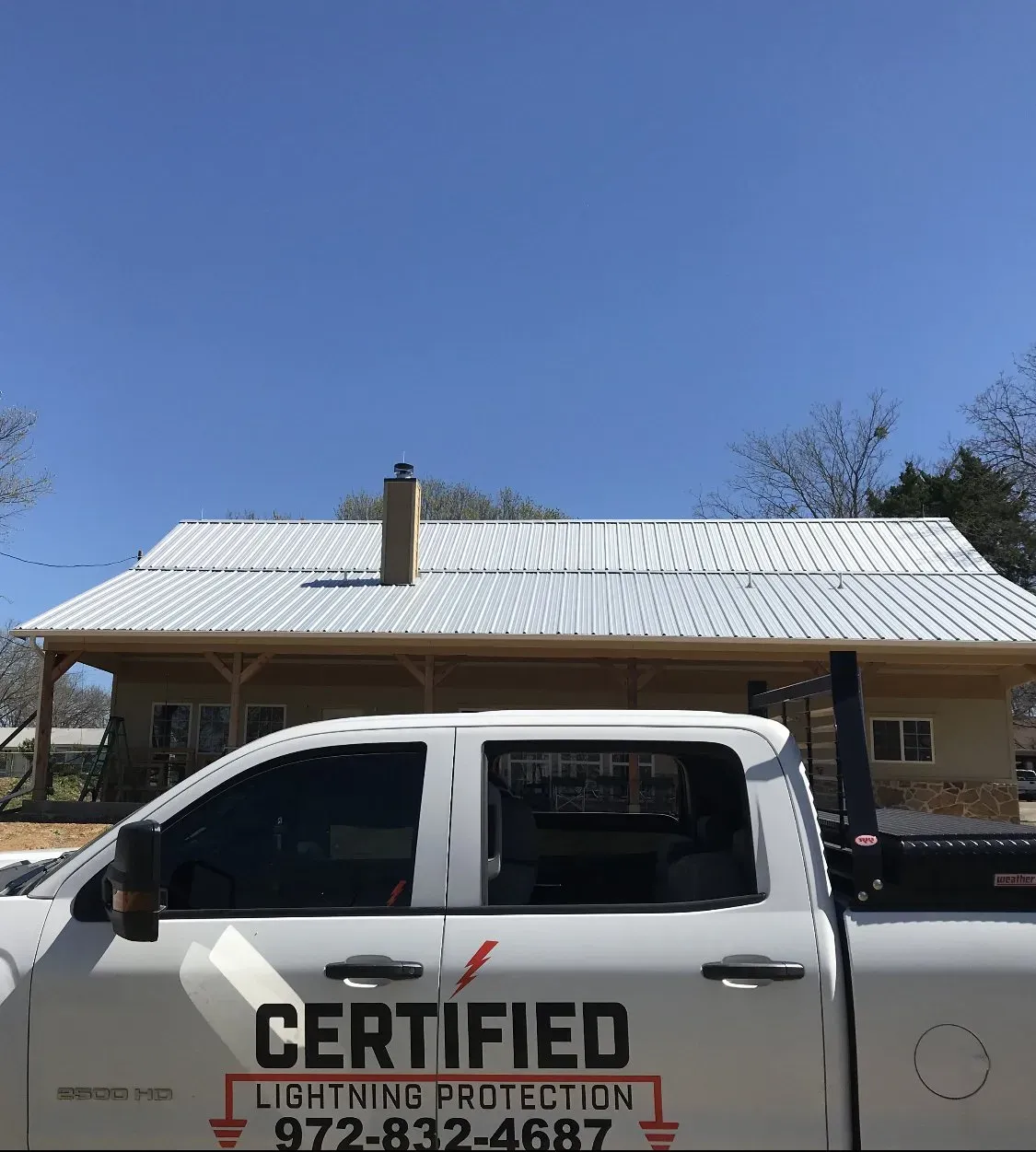 A certified lightning protection truck is parked in front of a house.
