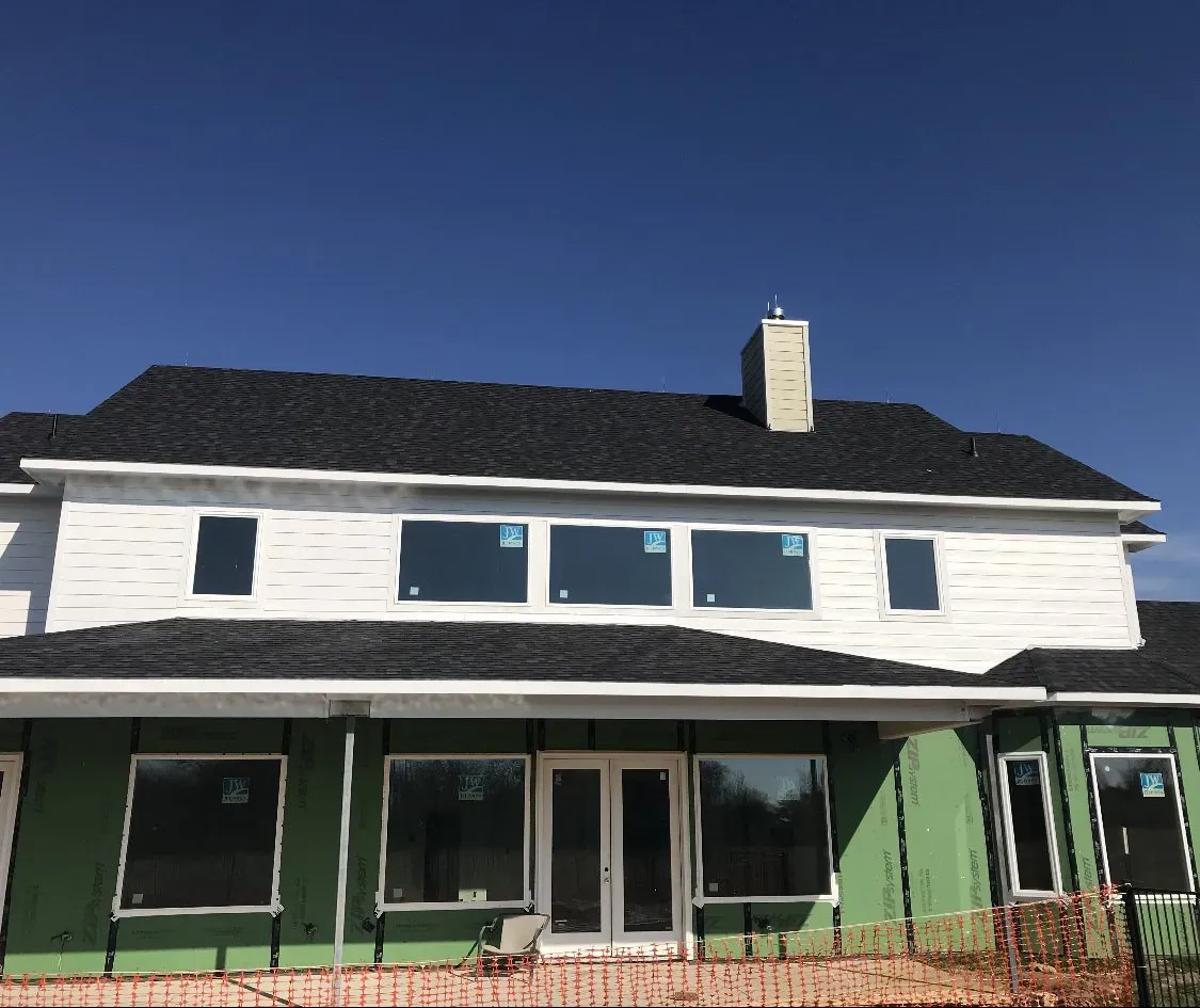 A white house with a black roof is being built.