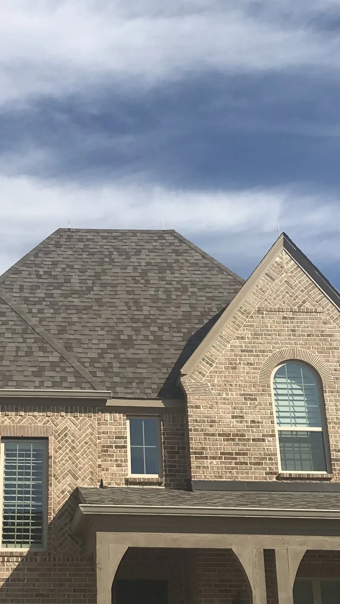 A large brick house with a gray roof and arched windows.