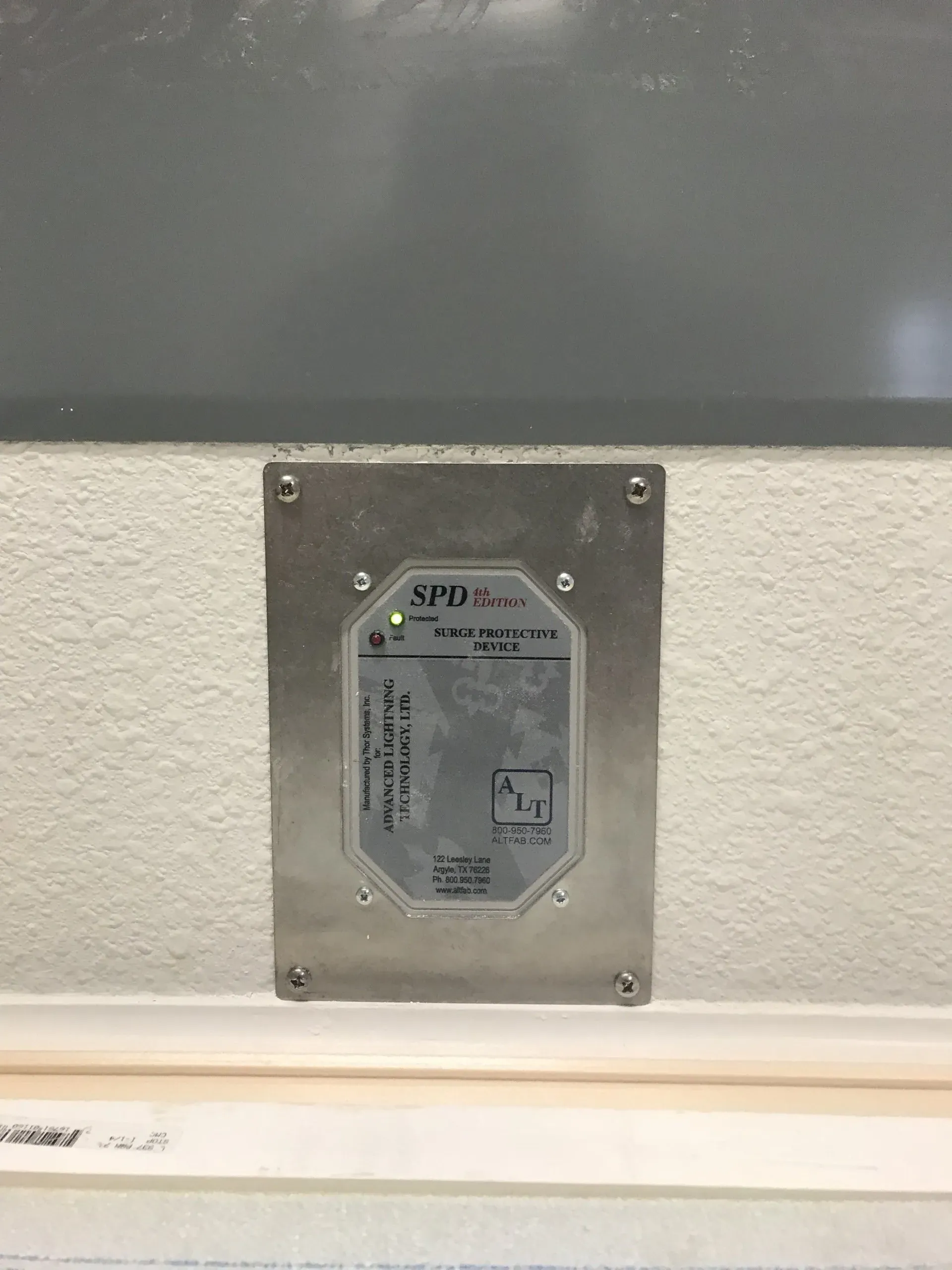 A stainless steel plate is sitting on a white wall next to a window.