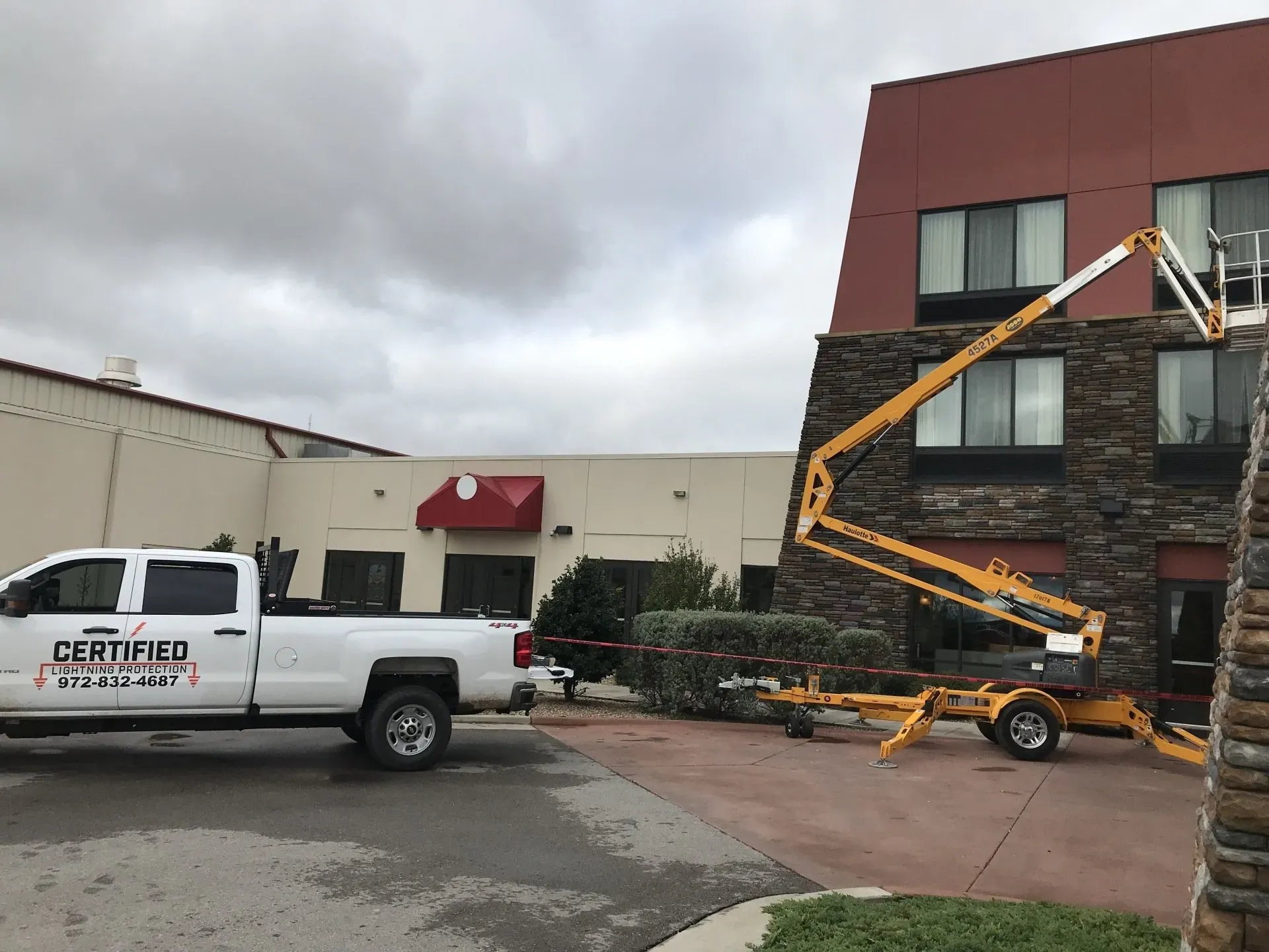 A white truck is parked in front of a building with a crane attached to it.