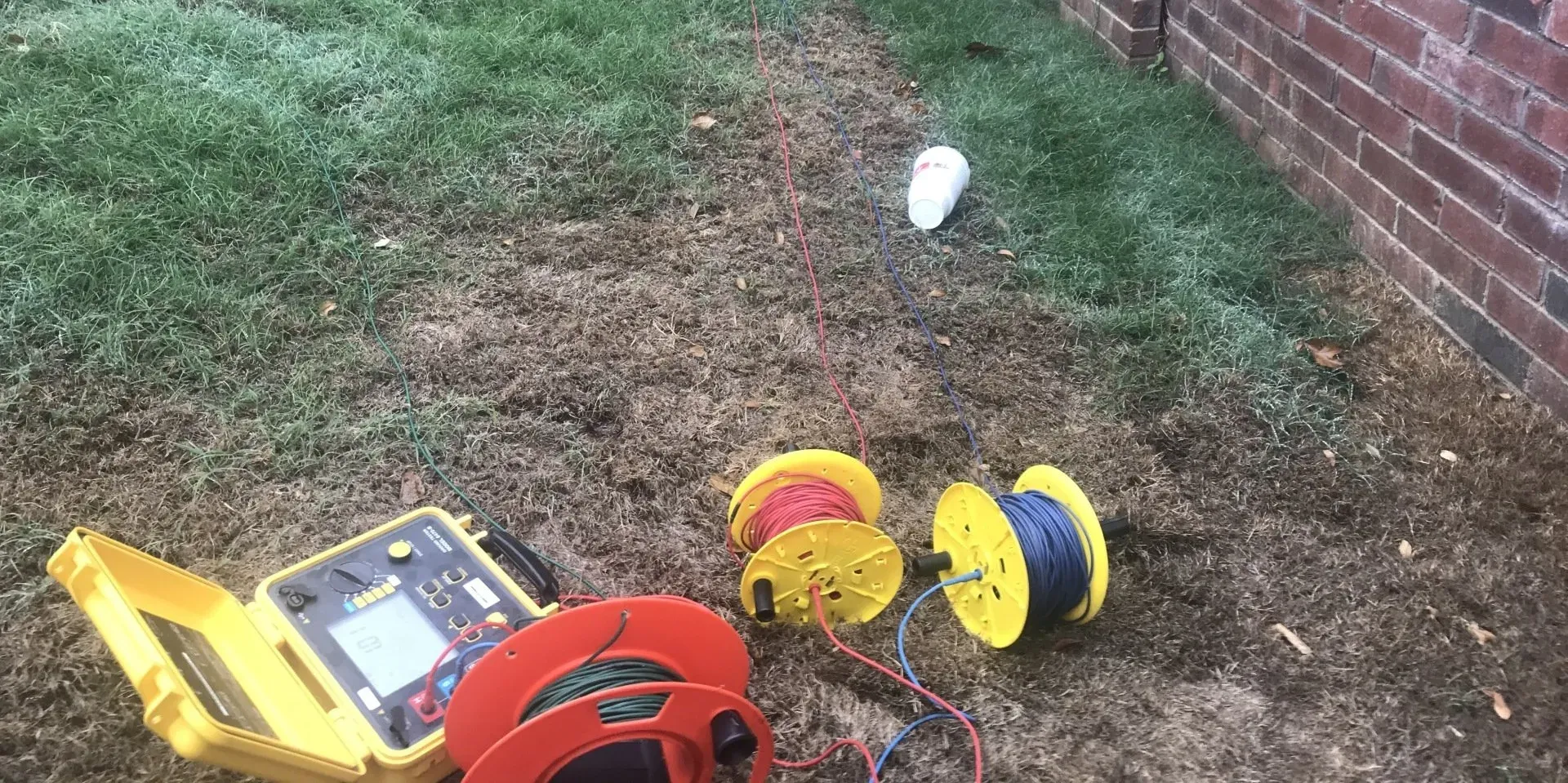 A bunch of wires are laying on the ground next to a brick wall.