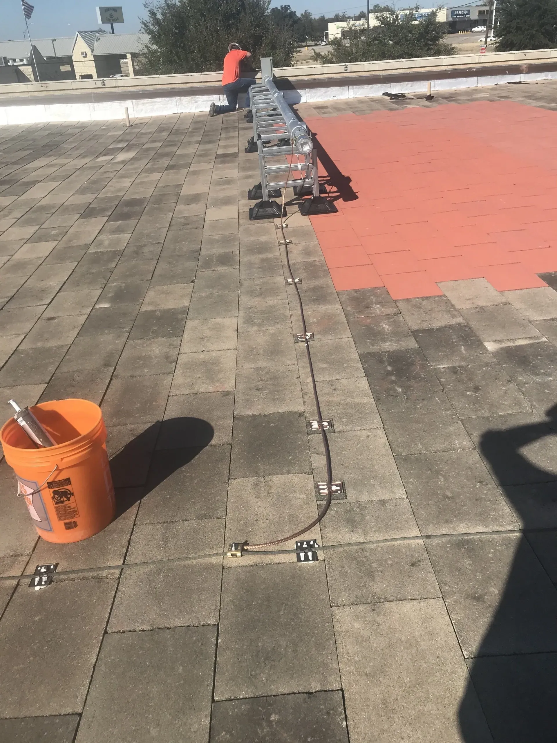 A bucket of paint is sitting on the ground next to a ladder.