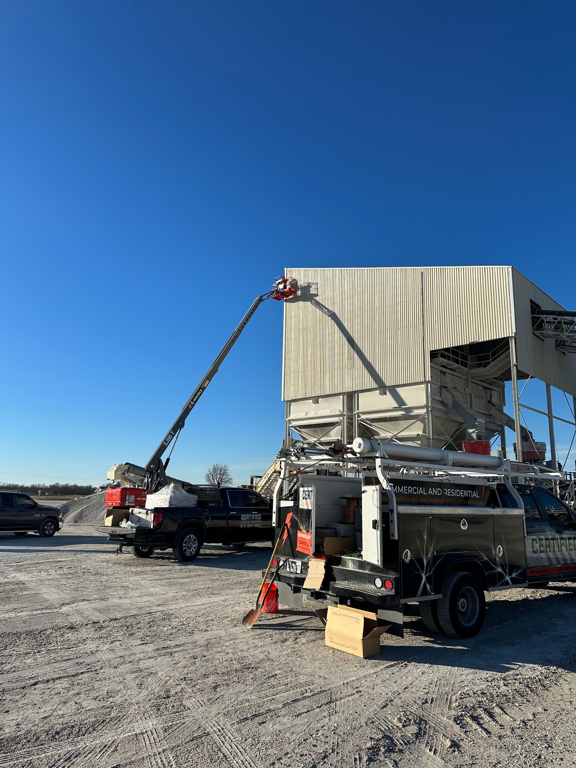 A truck is parked in front of a building with a crane on top of it.