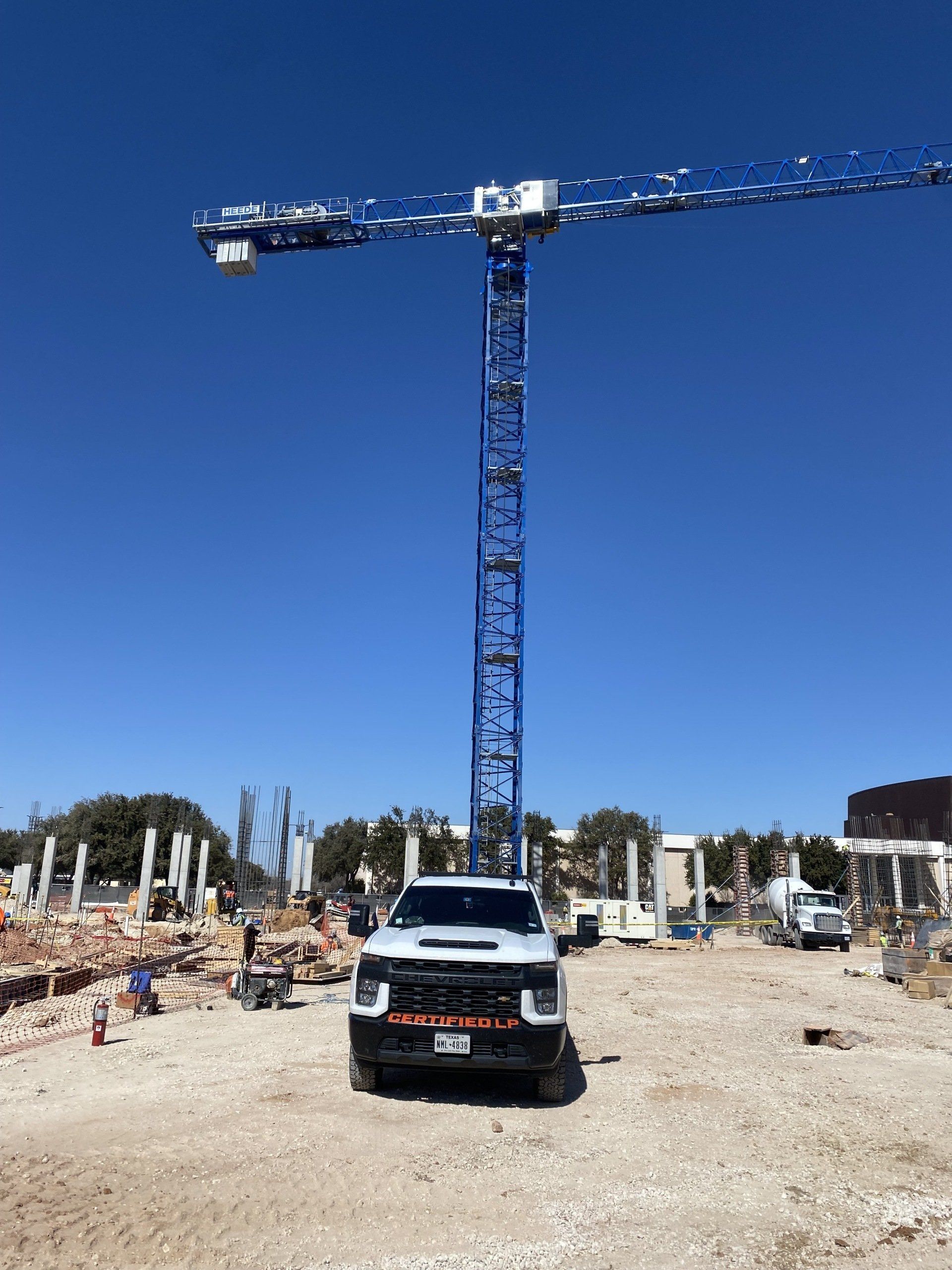 A truck is parked in front of a crane on a construction site.
