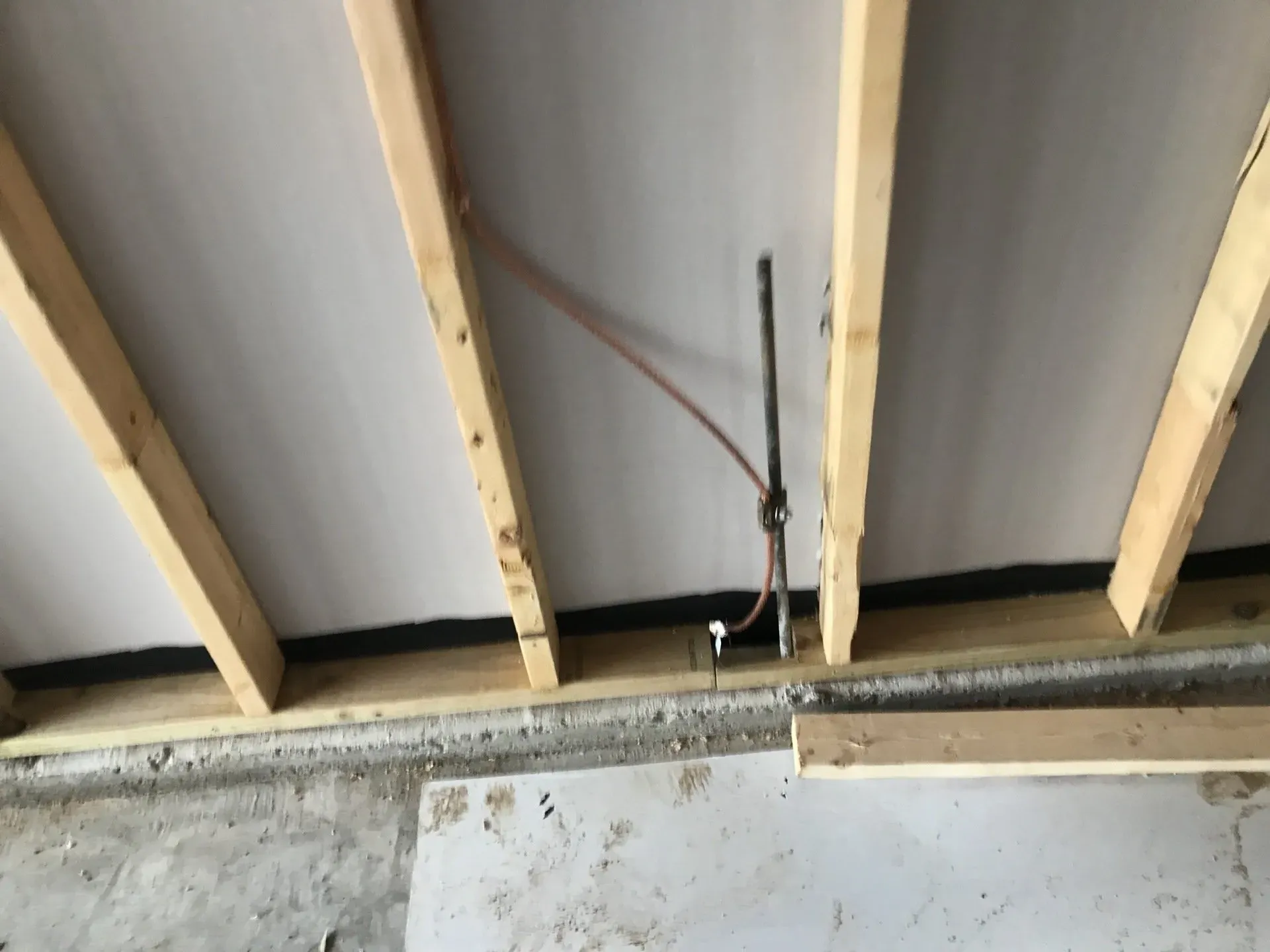 A ceiling with wooden beams and pipes coming out of it