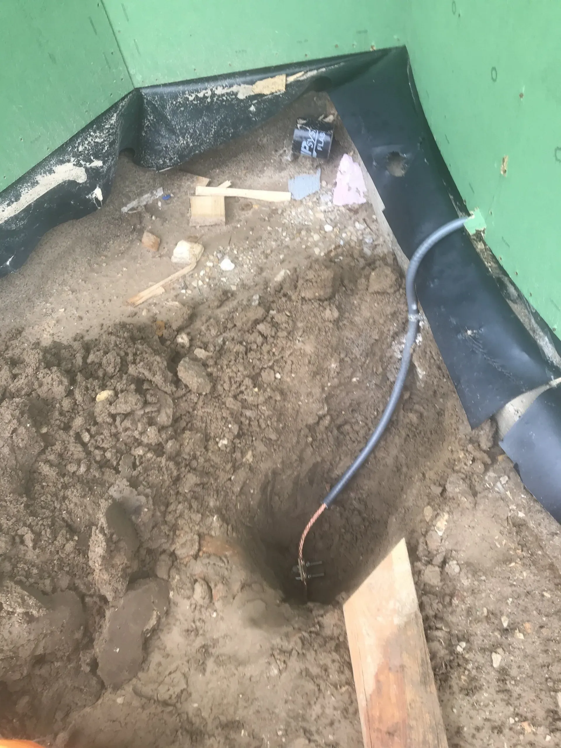 A hole in the ground with a wire sticking out of it.