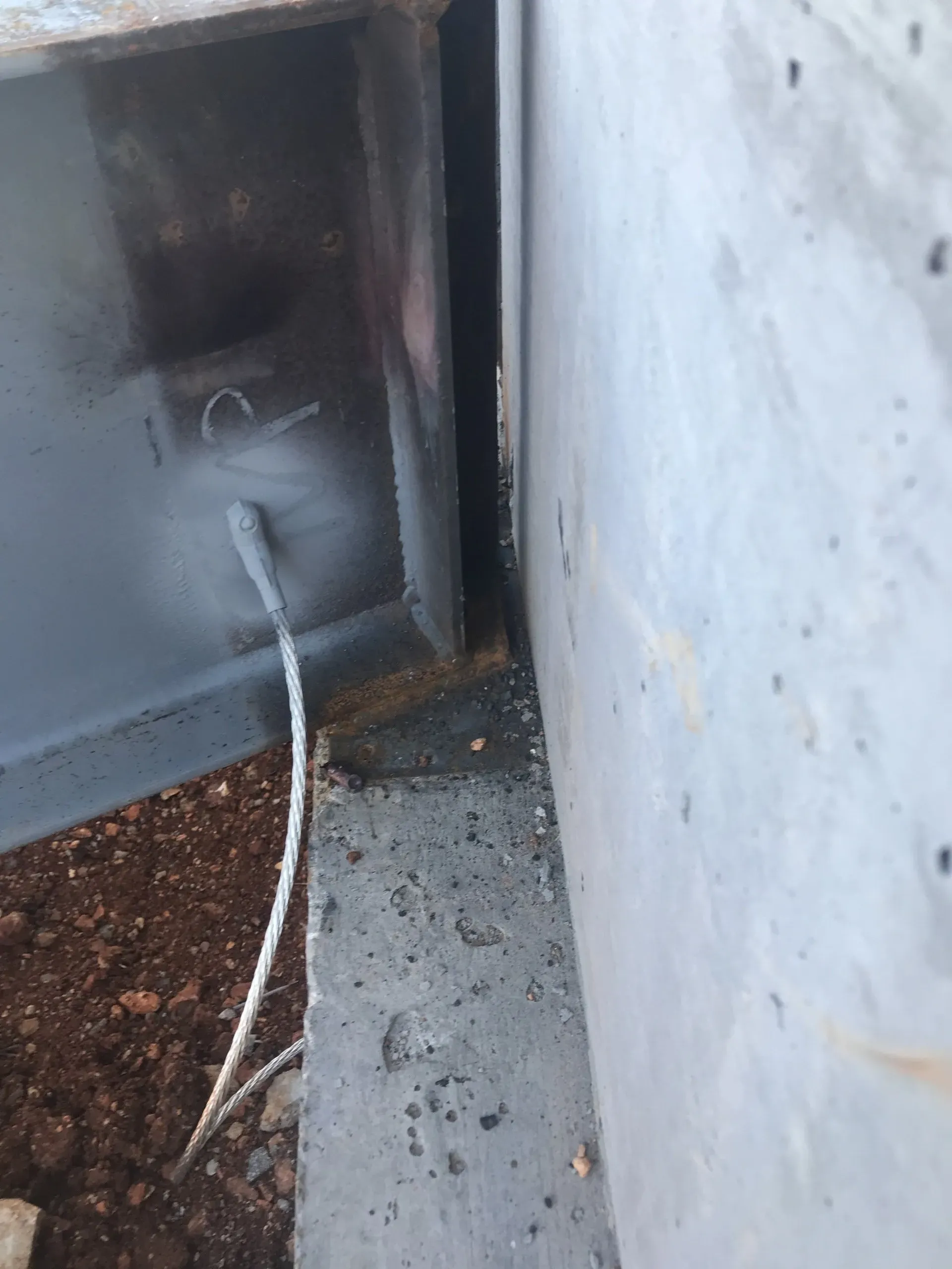A metal beam is sitting next to a concrete wall.
