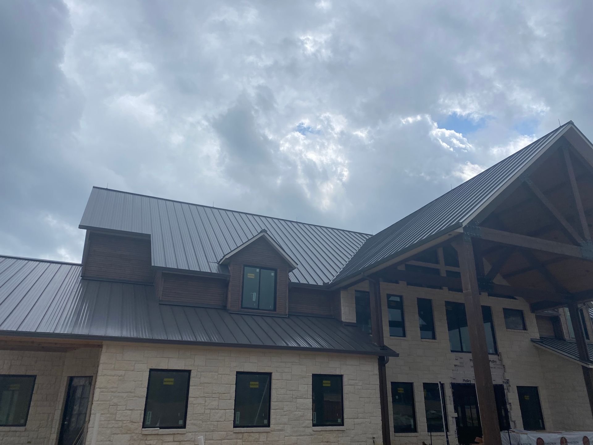 A large brick building with a metal roof is under construction.