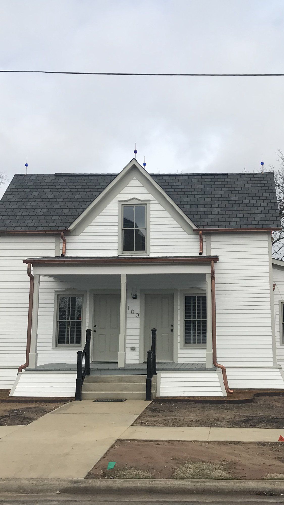 A white house with a gray roof and a porch.