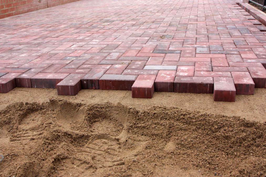 All-red block paving driveway with sand at the front.