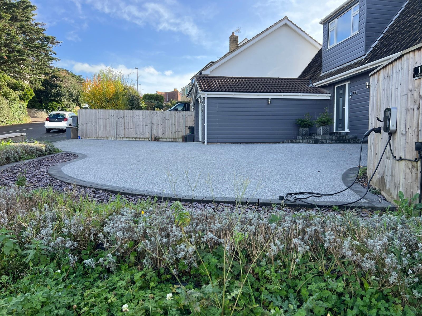 Curved, grey resin driveway with dark grey block paving border