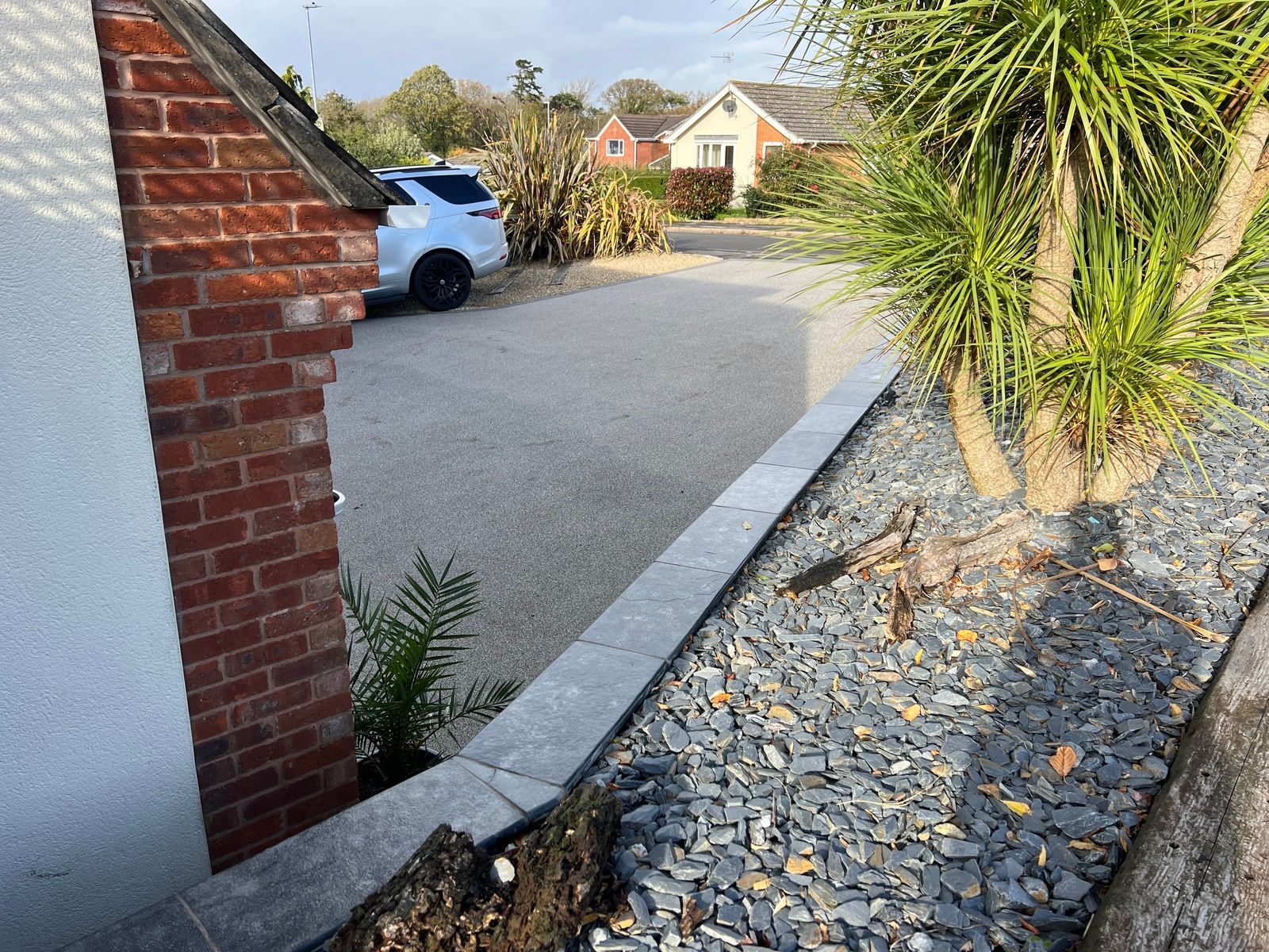 Grey resin driveway with car to the top and slate on the side