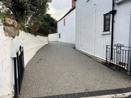 Long, grey resin driveway with black block paving border.