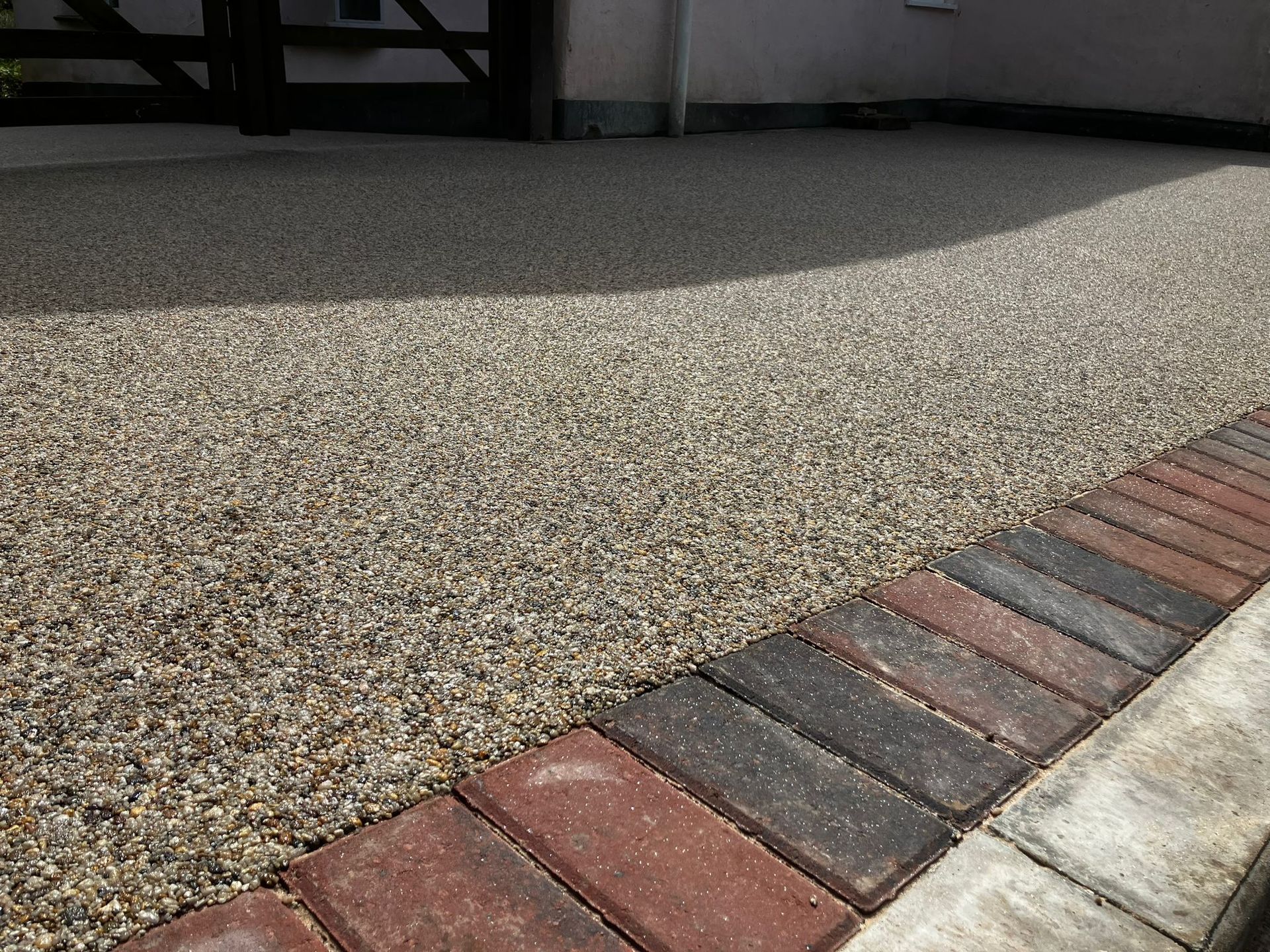 Close up of beige/grey resin driveway with red and brown block paving border