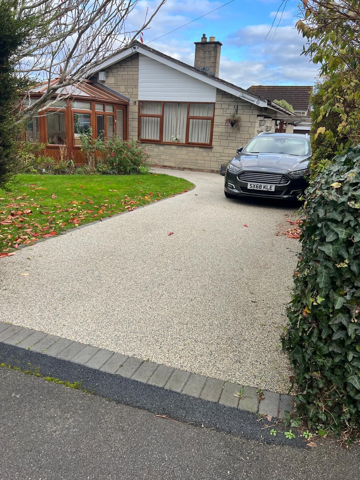 A car is parked in a driveway in front of a house.