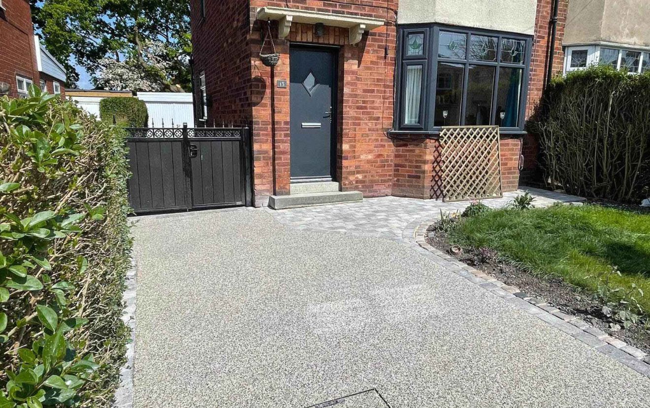 A driveway leading to a brick house with a black door.