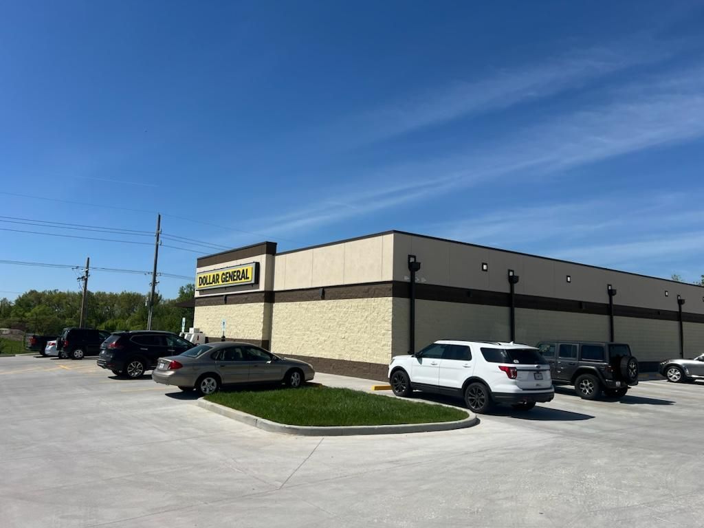 A row of cars are parked in front of a store.