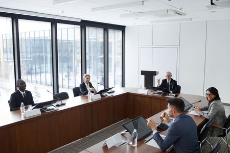 People seated around a conference table in a bright meeting room with large windows.
