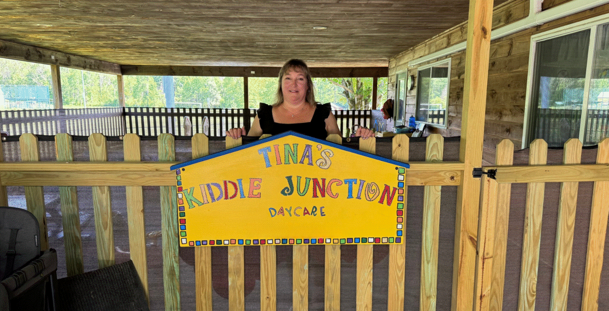 Woman standing behind a fence with a sign that reads