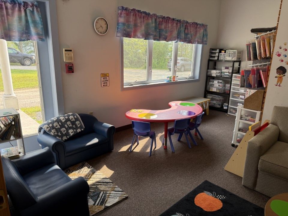 Playroom with colorful table, chairs, sofas, window, and storage shelves.