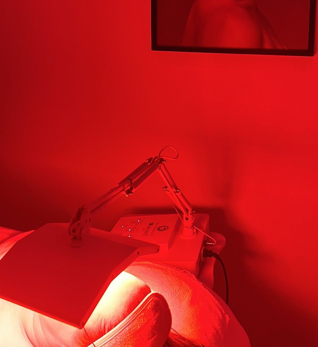 A Person Is Laying On A Bed In A Room With Red Lights On The Wall — Vanity Skin and Beauty Forster in Forster, NSW