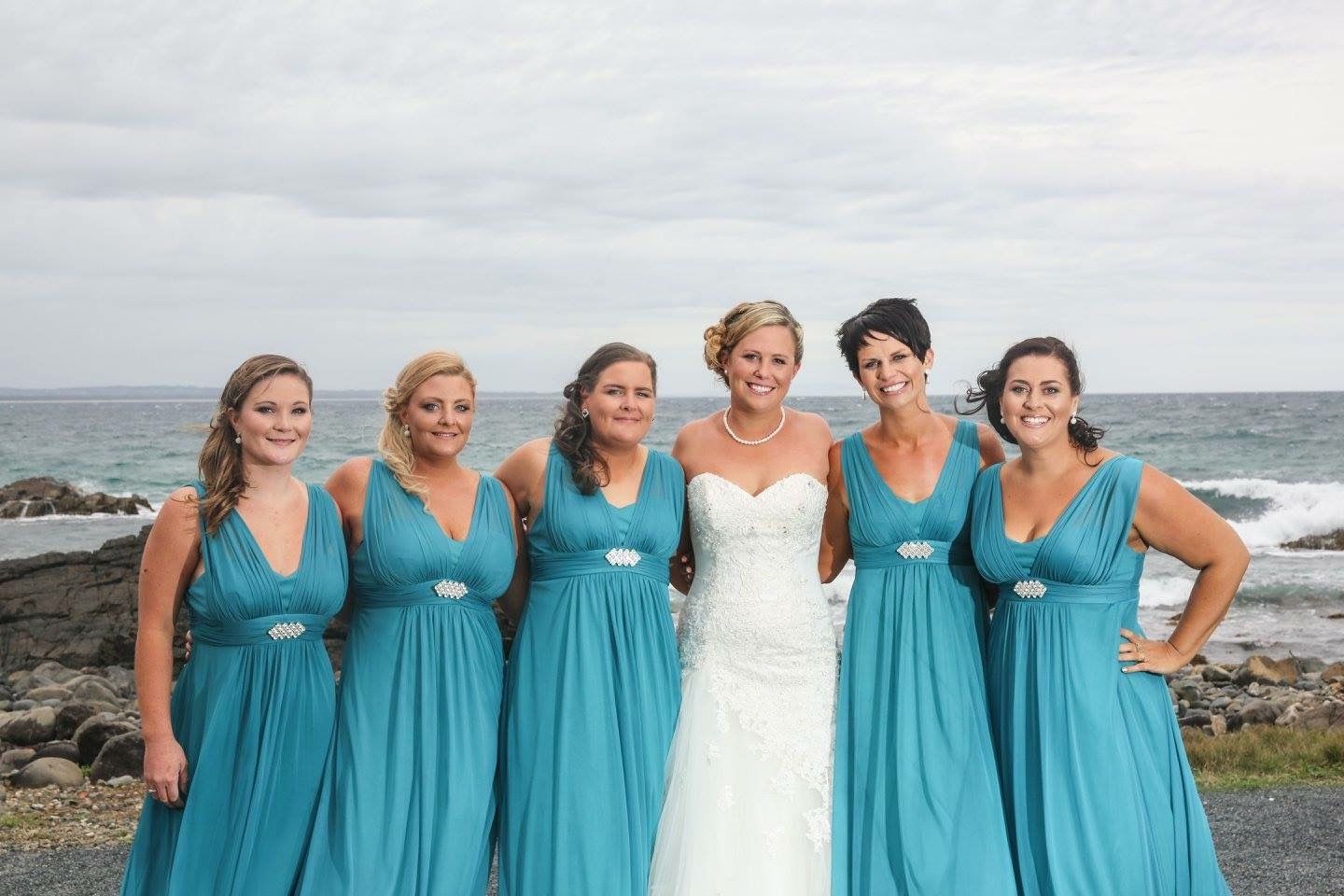 A bride and her bridesmaids are posing for a picture on the beach. — Vanity Skin and Beauty Forster in Forster, NSW