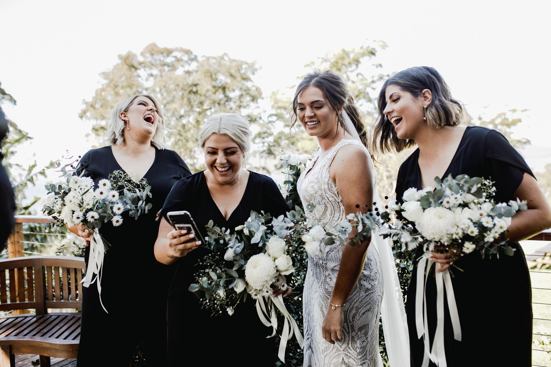 A bride and her bridesmaids are standing next to each other looking at their phones. — Vanity Skin and Beauty Forster in Forster, NSW