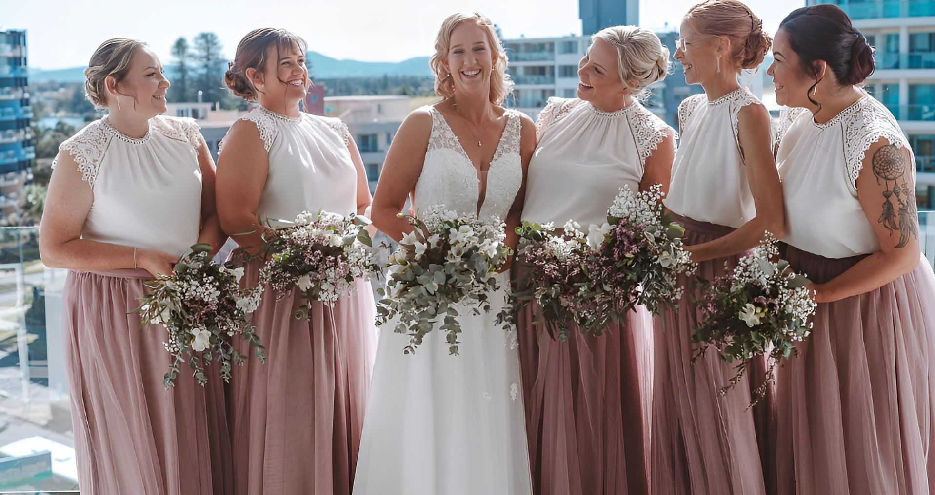 A bride and her bridesmaids are posing for a picture on a balcony. — Vanity Skin and Beauty Forster in Forster, NSW