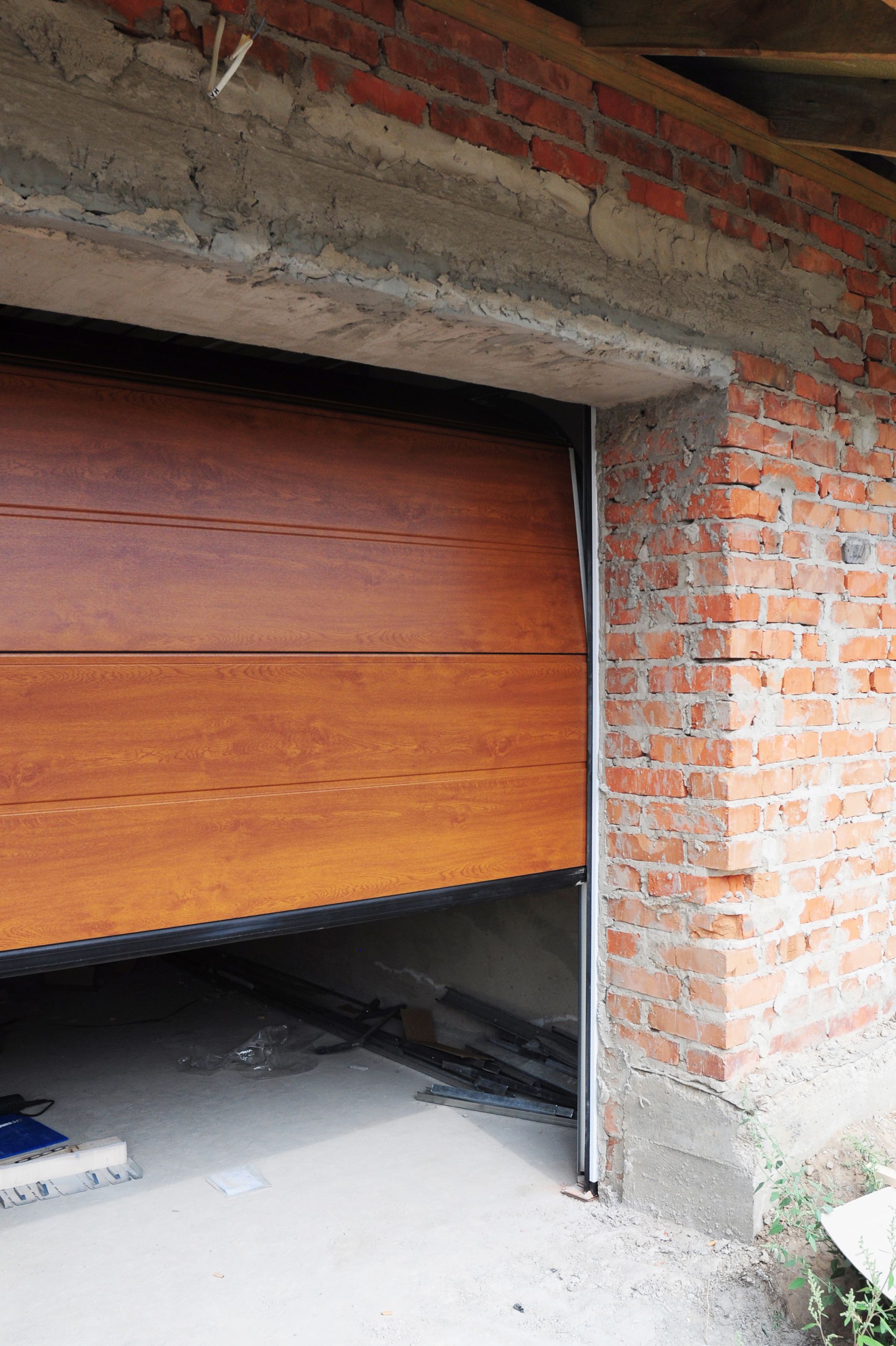 A wooden garage door is open in a brick building.