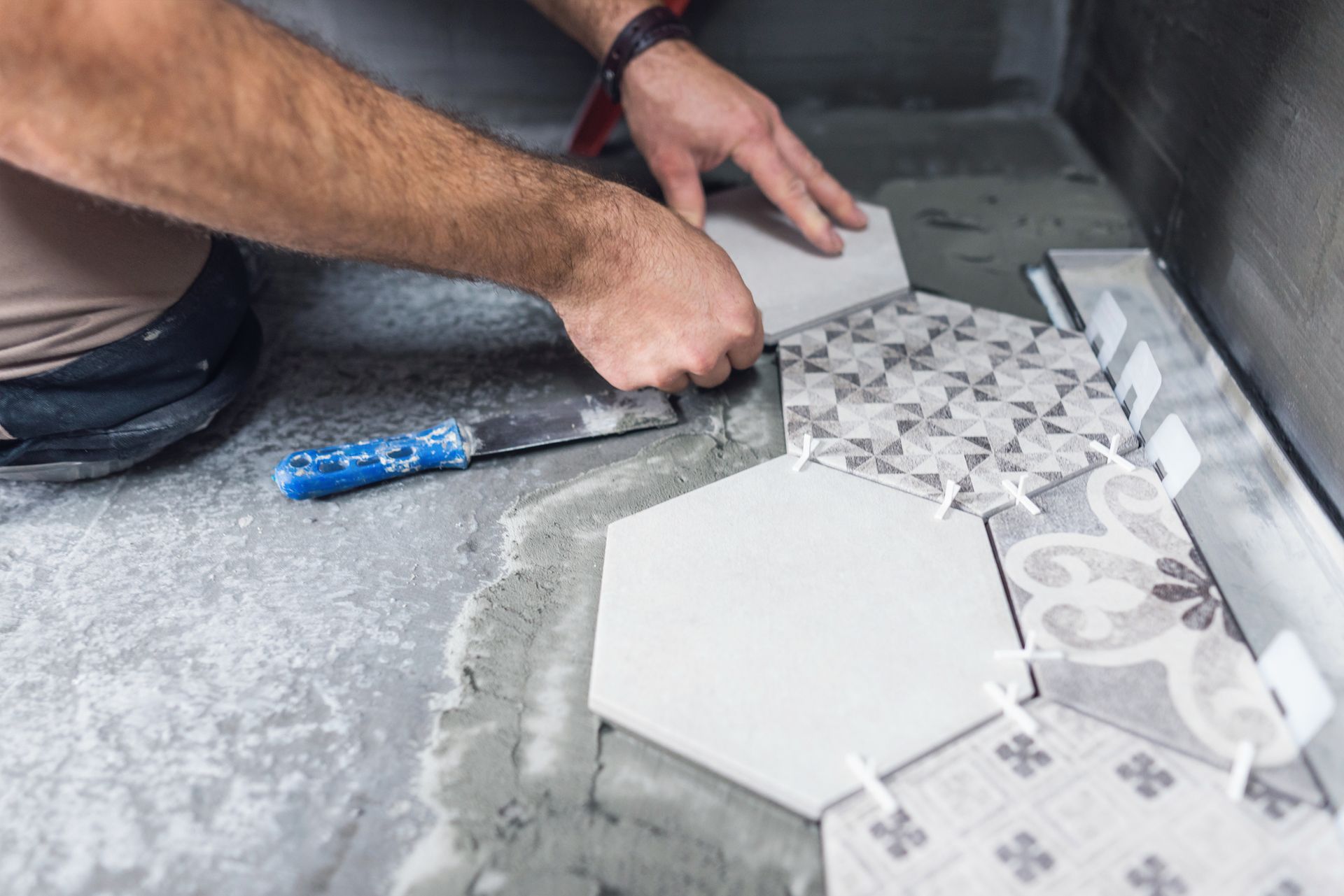 A man is kneeling on the floor with a toolbox full of tools.