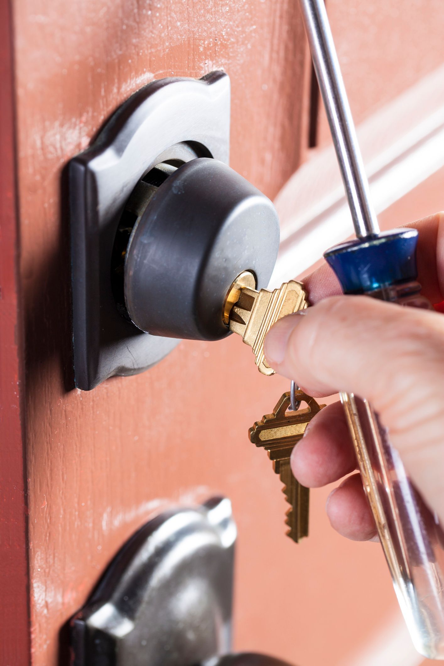 A person is fixing a door lock with a screwdriver.