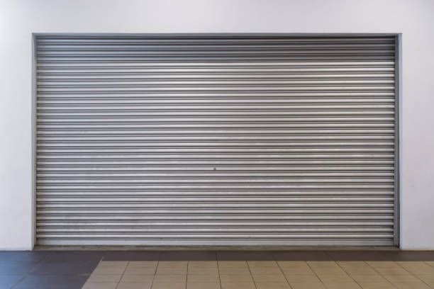 An empty store with a metal shutter on the door.