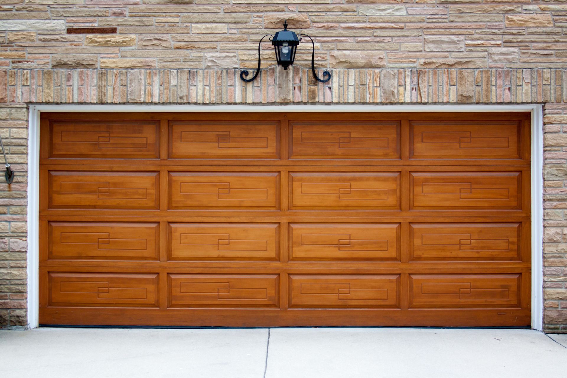 A wooden garage door is sitting in front of a brick building.