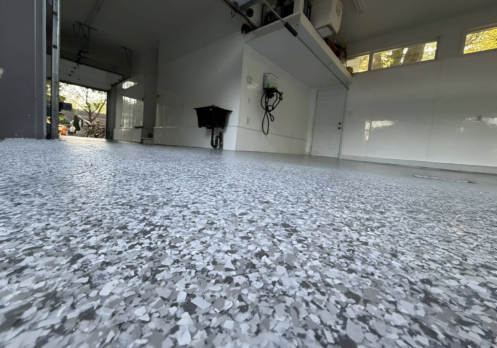 Sol époxy gris brillant dans un espace lumineux et vide de type garage avec une porte enroulable.