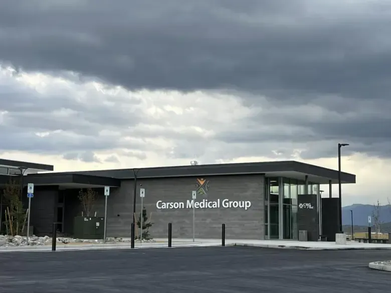 Large modern industrial building with gray and white facade under a blue sky.