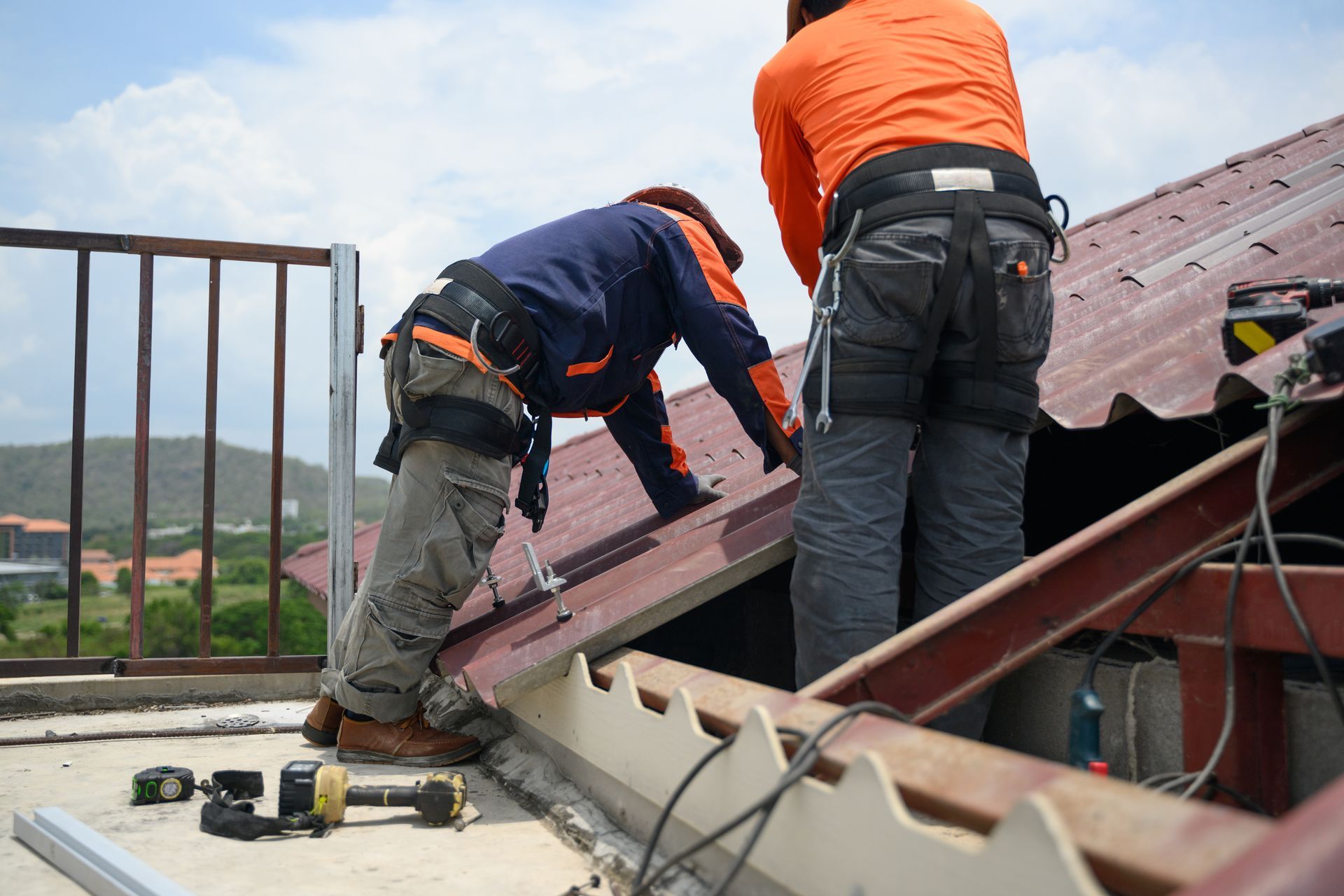 Construction worker on rooftop, using tablet, looking up; two people with blueprints and one in suit stand nearby.