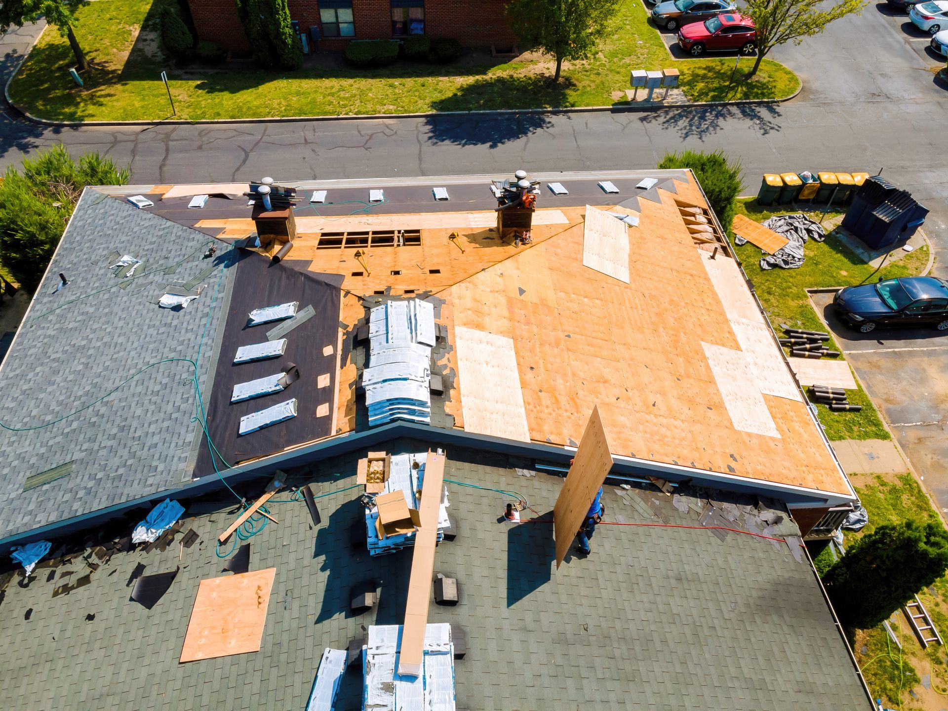 Person working on a wooden roof structure outdoors, using a tool.