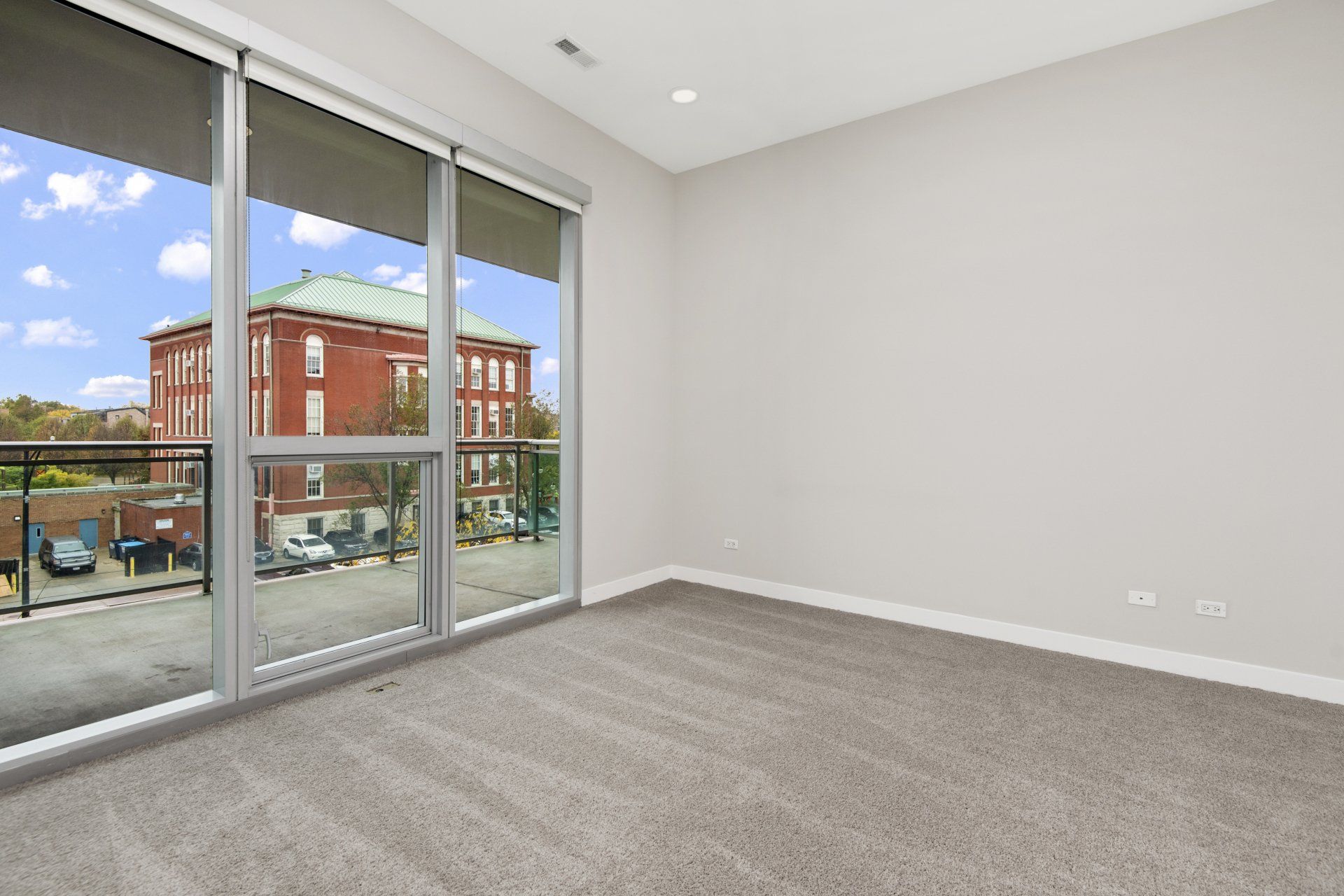 An empty room with a large window. balcony, and a view of a building at 1846 W Division Street.