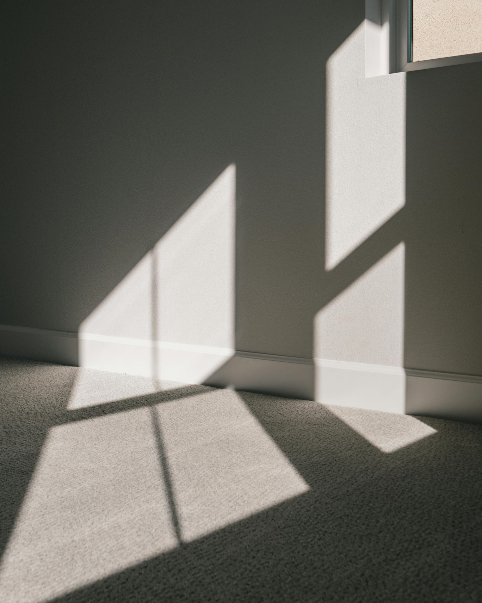 The sun is shining through the window and casting a shadow on the floor.