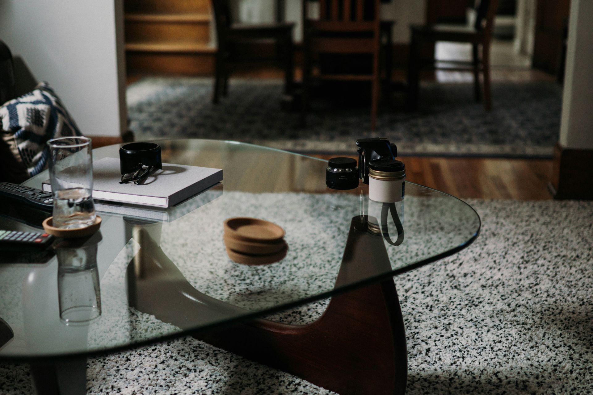 A glass coffee table is sitting on a rug in a living room.